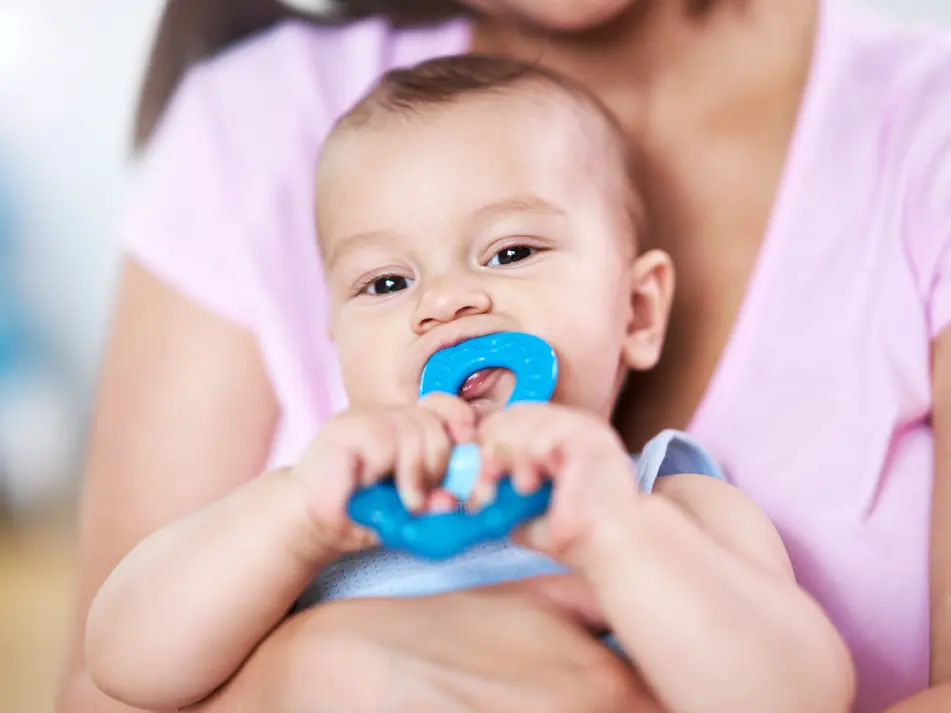 Baby chewing teething ring demonstrating teething signs and soothing tips